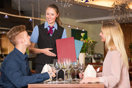 Waitress in restaurant presenting the menu to two guests